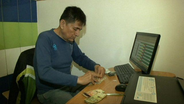 Prisoner/bank manger counting cash in Peruvian prison bank