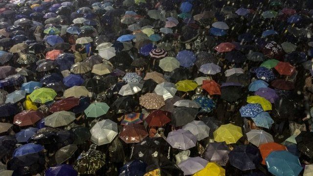Pro-democracy protestors use umbrellas to shield themselves from heavy rain in Hong Kong on September 30, 2014