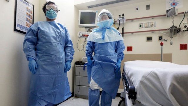 Medical workers pose in protective suits in an isolation room, in the Emergency Room of the Bellevue hospital