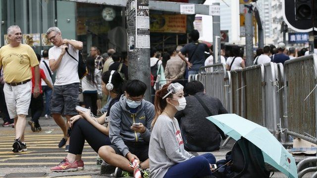 Pro-democracy protesters of the Occupy Central movement remain at an intersection as foreign nationals walk by in Mong Kok District of Hong Kong