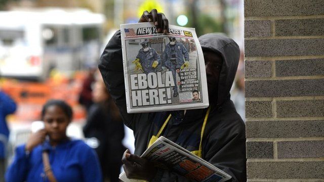 A newspaper vendor holds up a copy of the NY Post in front of the entrance to Bellevue Hospital.