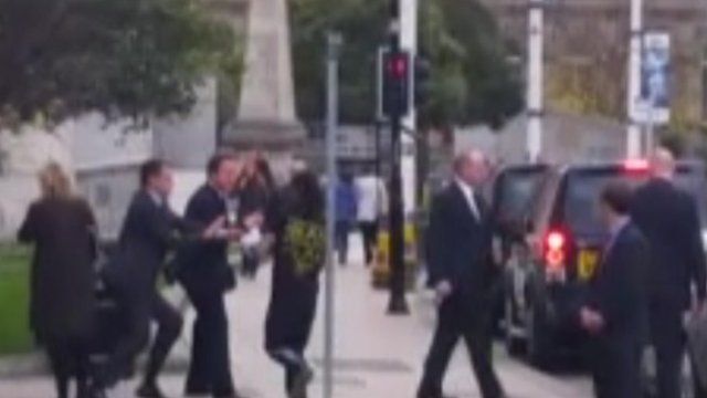 Still of a man running into David Cameron