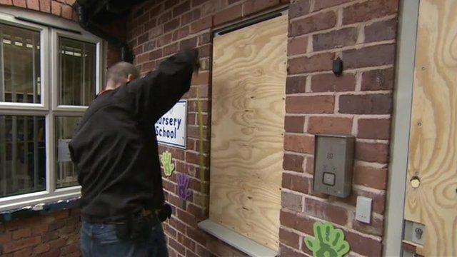 A workman boards up a broken window