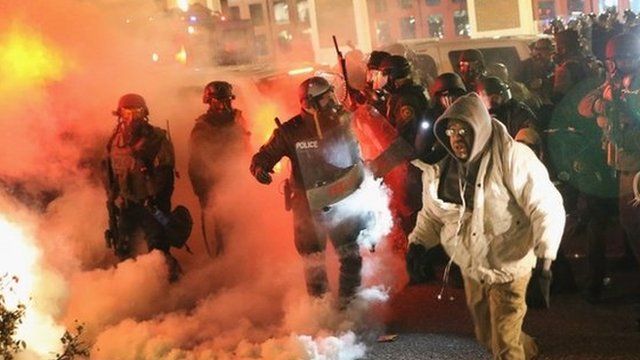 Police guard the Ferguson police department as rioting erupts following the grand jury announcement in the Michael Brown case on November 24, 2014