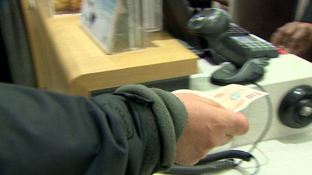 Man handing £10 note to a cashier in a shop