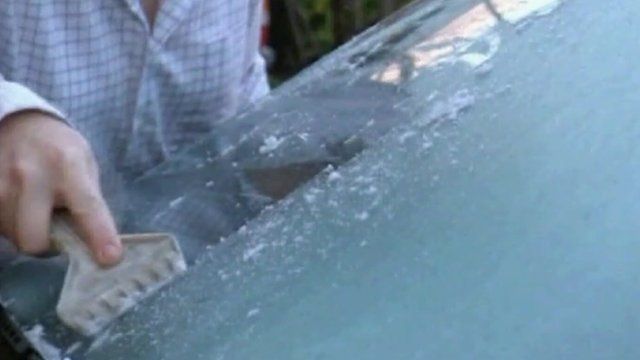 Man de-icing car windscreen