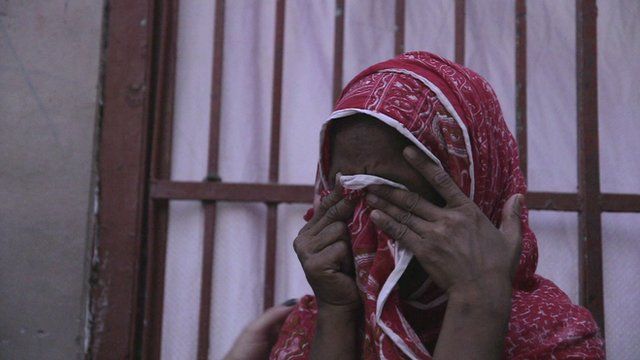 A woman covers her face as she cries