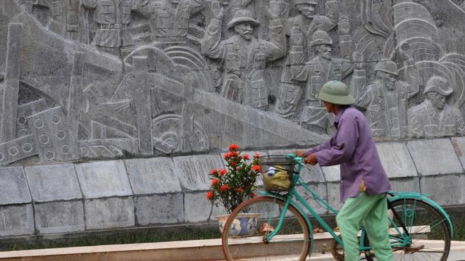 Một người đi qua tượng đài Điện Biên Phủ