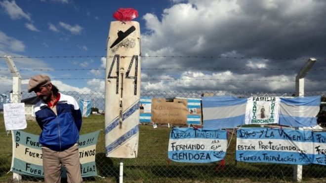A man stands in front of signs in support of the 44 crew members of the ARA San Juan submarine missing at sea, placed on a fence outside the Argentine Naval Base where the submarine sailed from, in Mar del Plata, Argentina November 20, 2017.
