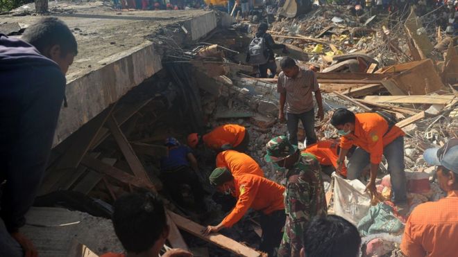 Petugas berusaha menemukan warga yang diperkirakan terperangkap di bawah reruntuhan bangunan yang ambruk setelah gempa hari Rabu (07/12) di Pidie Jaya, Aceh.