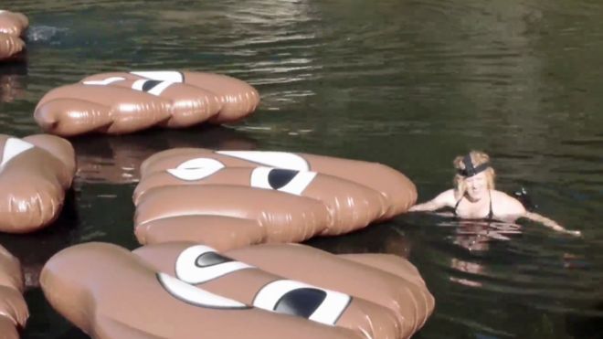 An Action Station member swims with poo emojis in Lake Ohakuri