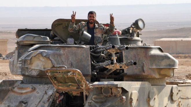 A soldier from the Syrian government forces flashes the 'V' for victory sign in the eastern Syrian city of Deir Ezzor during an operation against Islamic State (IS) group jihadists