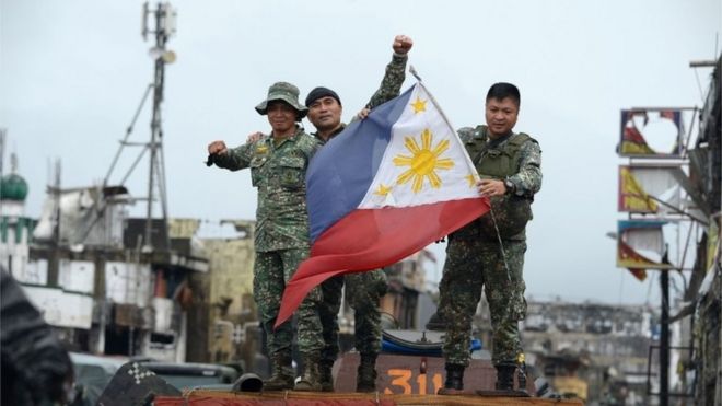 Philippine soldiers aboard their armoured personnel carrier celebrate after President Rodrigo Duterte declared Marawi City "liberated", inside the battle area of Bangolo in Marawi on October 17, 2017.