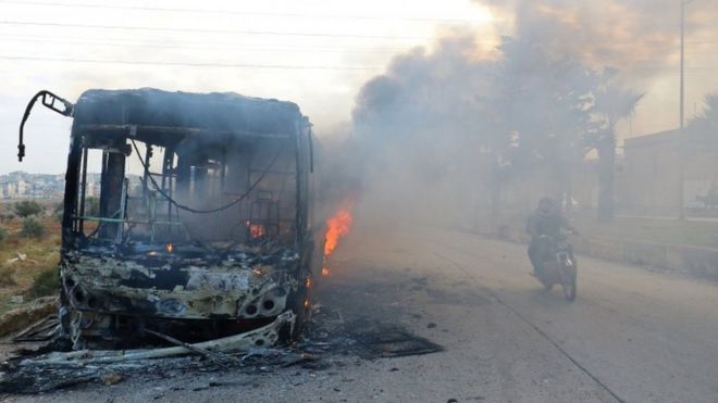 A man on a motorcycle drives past burning buses while en route to evacuate ill and injured people from the besieged Syrian villages of al-Foua and Kefraya, after they were attacked and burned, in Idlib province, Syria 18 December 2016