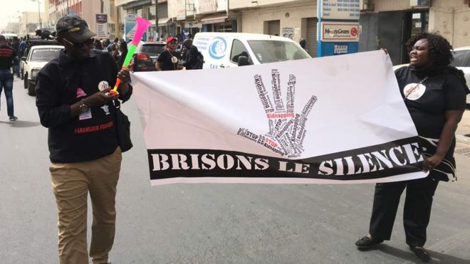 Des membres du Collectif pour la protection de l'enfant (CPPDE), de noir vêtus, tiennent une banderole sur lequel il est écrit: "Brisons le silence".
