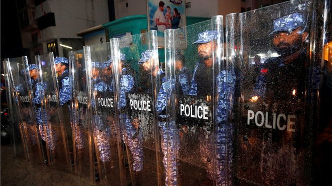 Maldivian police stand guard on a main street during a protest by opposition supporters