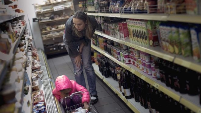 Mujer mirando productos en una góndola del supermercado.