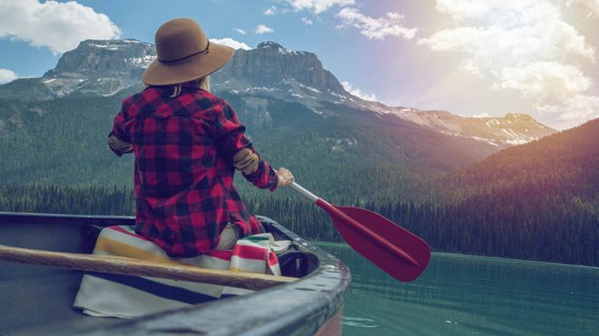 A young woman canoeing on beautiful mountain lake in Canada