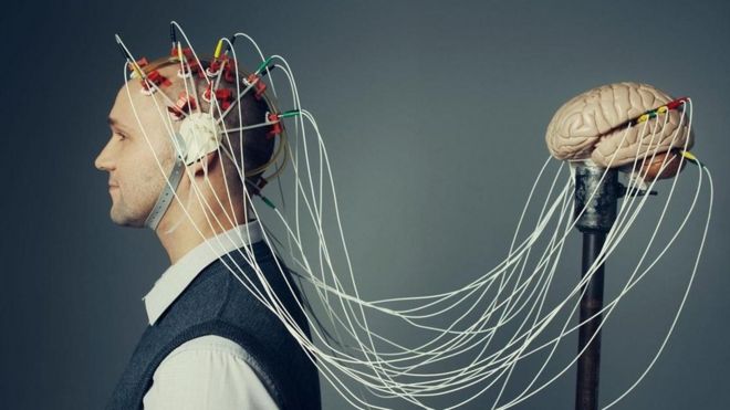 Una persona con cables conectados de su cabeza a un cerebro de plástico