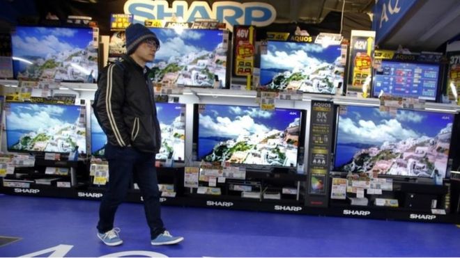 A shopper walks in front of Sharp"s Aquos flat-panel TVs at an electronics store in Tokyo, Thursday, Feb. 25, 2016