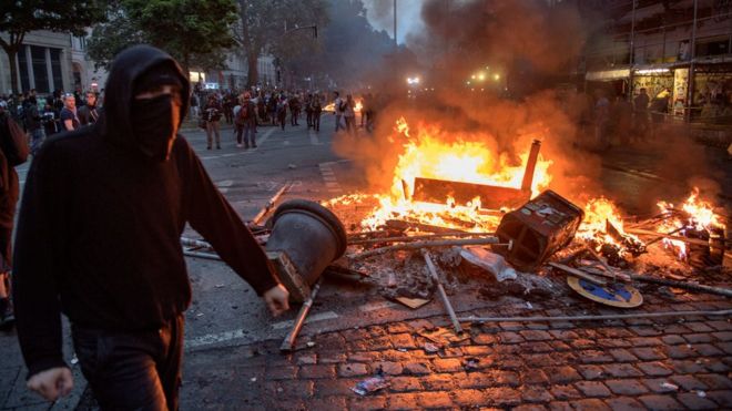 Demonstrators react next to a burning crush barrier during a demonstration against the G20 Summit in Hamburg, Germany, 7 July 2017