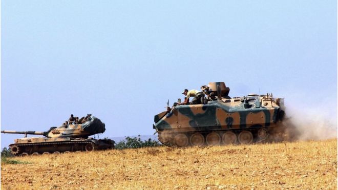A Turkish army tank and an armored vehicle are stationed near the border with Syria