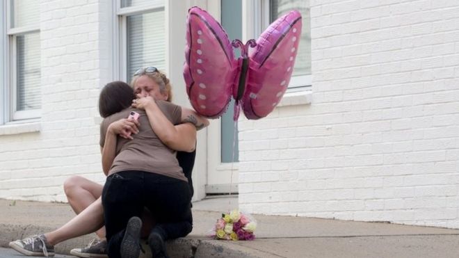Mulher chora em frente a flores no local onde uma mulher morreu e 19 pessoas ficaram feridas, em Charlottesville, EUA