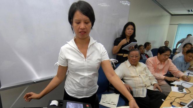 An employee (L) of Smartmatic demonstrates the function of election automation machine next to Philippine Commission on Elections (Comelec) officials