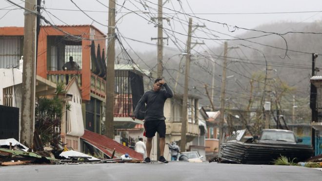 A man reacts as he walks through a debris-covered road in Fajardo, Puerto Rico.