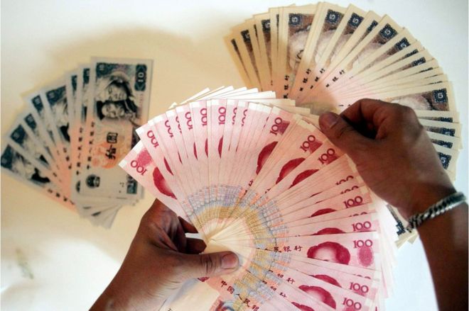A man lays out the various denominations of the Chinese yuan, in Beijing 8 June 2005.