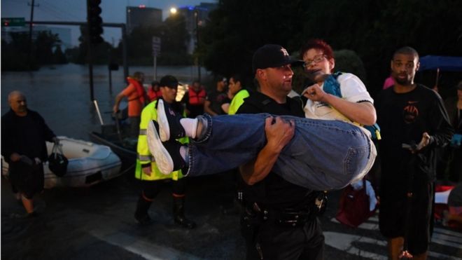 Un hombre carga a una mujer luego de evacuarla de un hotel en bote por las fuertes lluvias de la tormenta Harvey en Houston.