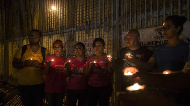 Activists pray at the wall between Mexico and US during a protest against the possibility of deportation of "Dreamers" in Playas de Tijuana, Baja California, Mexico, 4 September