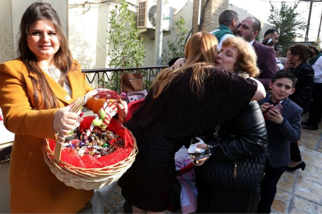 مسيحيون ومسيحيات في مدينة بغداد يتبادلون الحلوى.