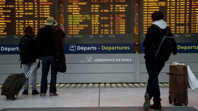 People watching departure boards at Paris Charles de Gaulle airport