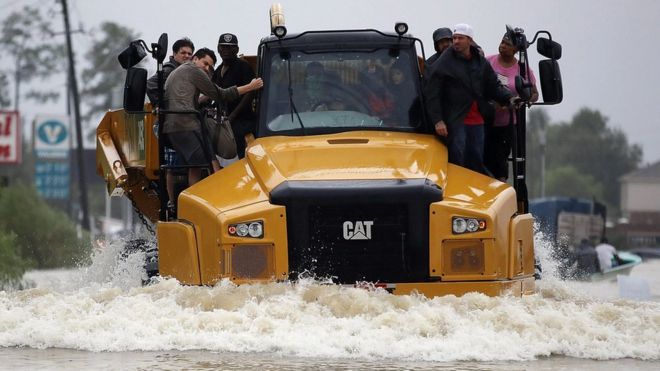 Un grupo de personas se sube a un camión de construcción para atravesar una zona inundada en Houston, Texas.