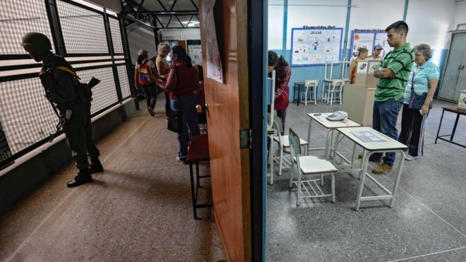 A soldier (L) stands guard as people vote to elect a Constituent Assembly in Caracas on July 30, 2017