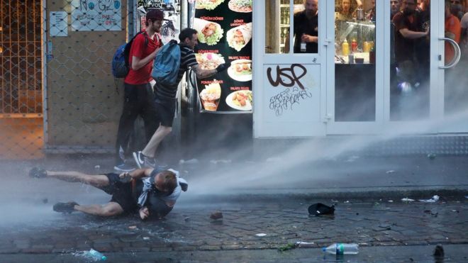 A man lies on the ground as riot police use water cannon against protesters on July 7