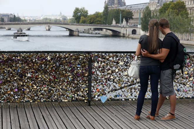 Paris'te köprüdeki kilitlerin önünde sarılmış bir çift
