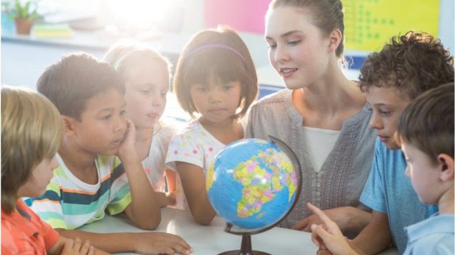 Children and teacher look at globe