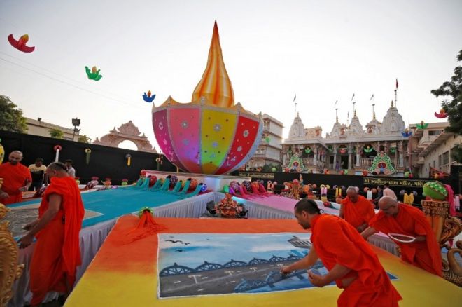 அகமதாபாதின் ஆலயம் ஒன்றில் வண்ணக் கோலங்களாய் ரங்கோலியை உருவாக்கும் பூசாரி.