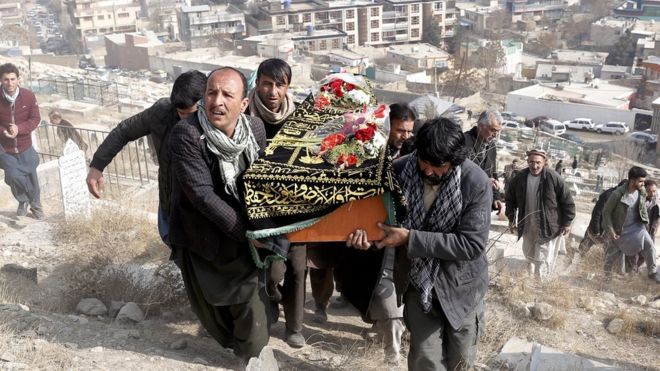 Un grupo de hombres suben una colina con un ataúd, dejando atrás los edificios de Kabul.