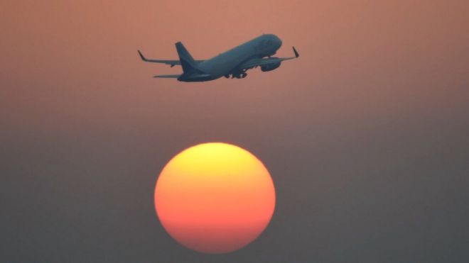 Avión sobrevuela el cielo con el sol de fondo.