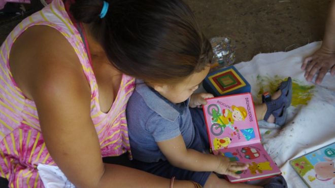 mãe e filho de 1 ano e 5 meses brincam com livro infantil sentados no chão (foto: Amanda Rossi/BBC Brasil)