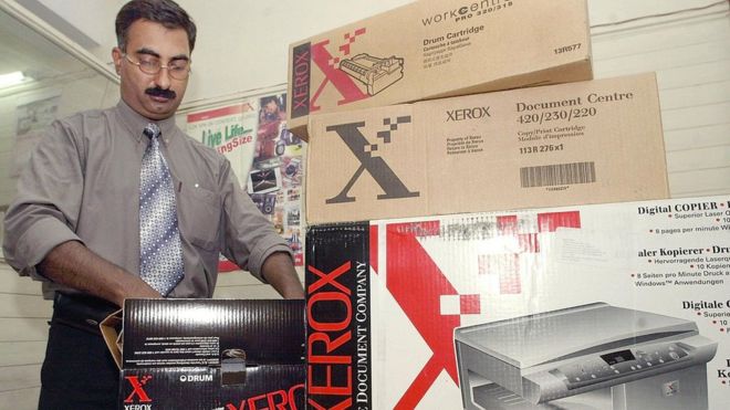 Un hombre desempaca un toner para fotocopiadoras Xerox.