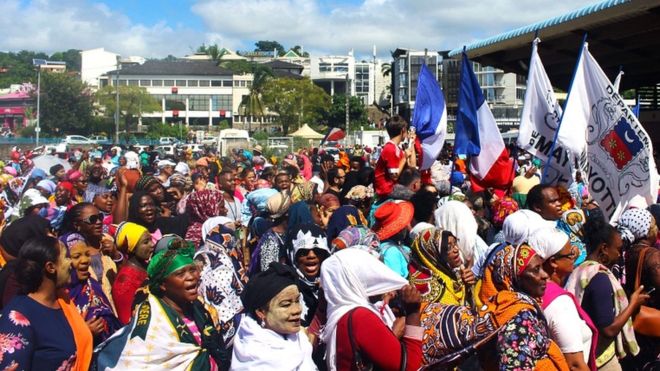 Protesters hold French and Mayotte flags as they gather on the Place de la Republique in Mamoudzou, Mayotte, on 13 March 2018