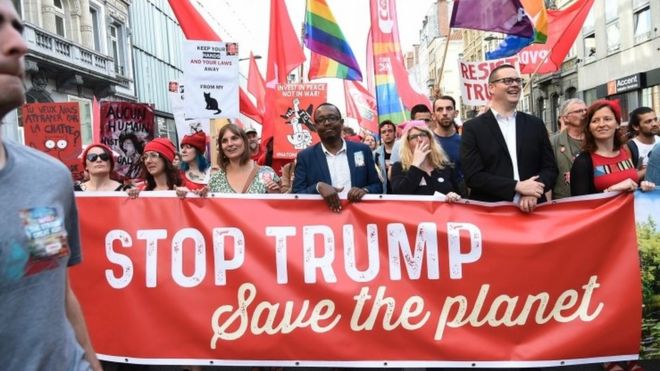 Protesters hold a banner as they take part in a demonstration against the US president in Brussels on May 24, 2017