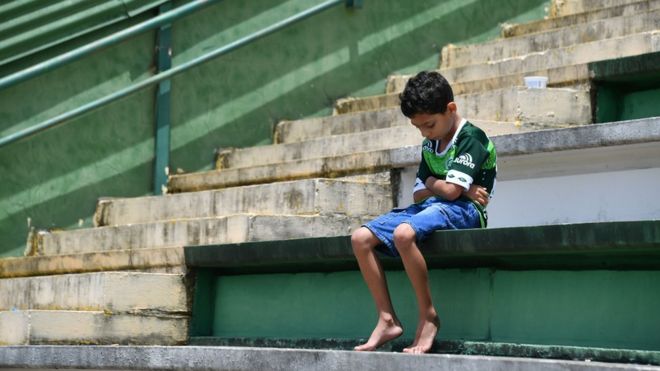 A boy sits alone on the stands during a tribute to the players of Brazilian team Chapecoense Real who were killed in a plane accident in the Colombian mountains