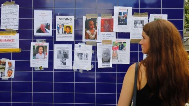 a woman looks at posters of the missing