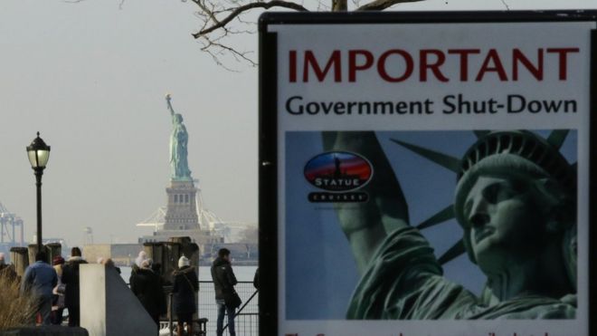 A Shutdown placard is seen at the entrance of the Liberty State ferry terminal as people look on in Battery Park on January 21, 2018 in New York City.
