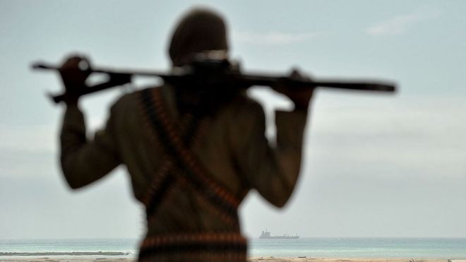 Mohamed Garfanji, Somalia's top pirate boss, stands on sandy dunes just outside the central Somali coastal town of Hobyo as he watches the outline of a hijacked ship anchored off the coast on August 20, 2010